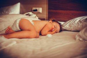 Innocent little child with nipple sleeping in bed