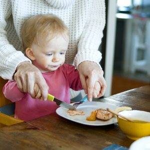 Woman in White Sweater Helping Baby Cut Food